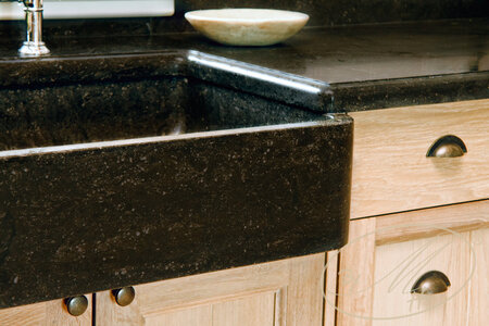 Material: oak veneer, solid oak, oil. Sink and worktop: Belgian blaustein. Detail of kitchen with sink.